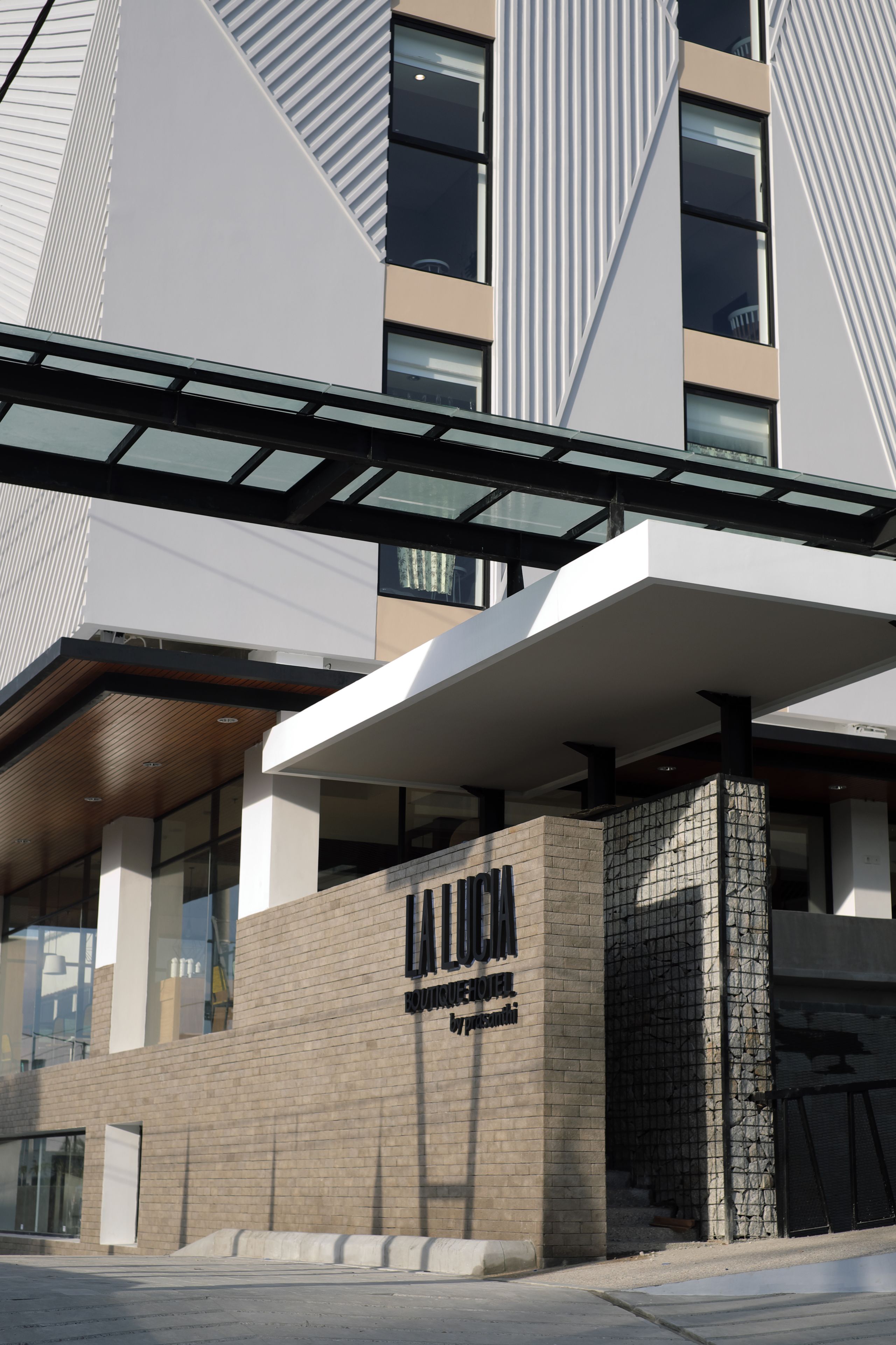 Un edificio moderno con una entrada destacada, un letrero que dice "LA LUCA" y una marquesina.