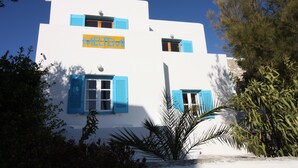 A white building with blue shutters and a sign that reads "MELTEMI". - Meltemi Studios and Apartments (Paros)