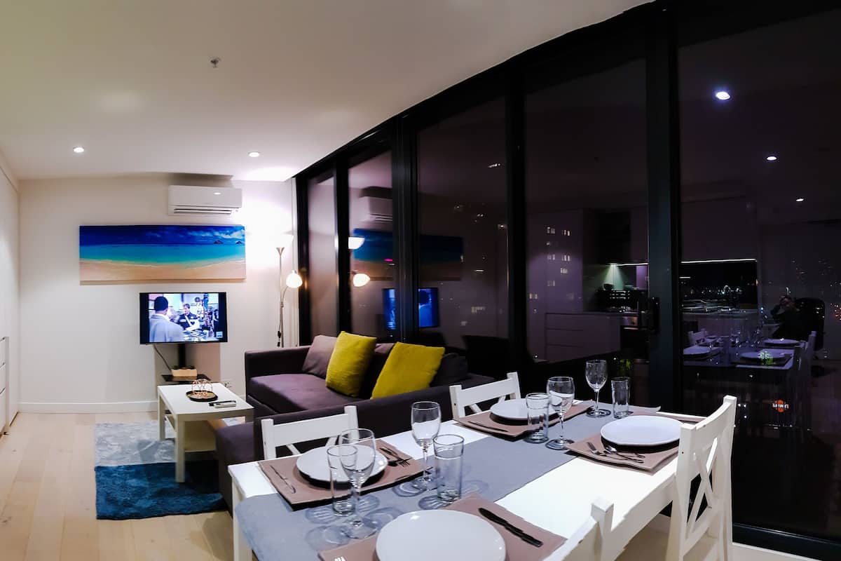 Una sala de estar moderna con comedor, cocina y un amplio ventanal con vistas a la ciudad.