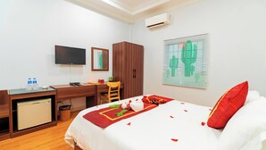 Une chambre d’hôtel comprenant un lit, un bureau avec un ordinateur, une télévision et une armoire.