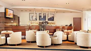 A hotel lobby with a bar area, seating arrangements, and artwork on the walls.