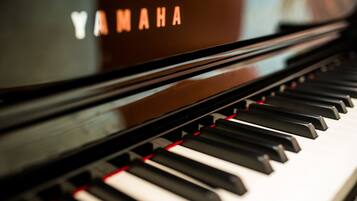 Primer plano de un piano Yamaha con un acabado negro brillante y detalles rojos en las teclas.