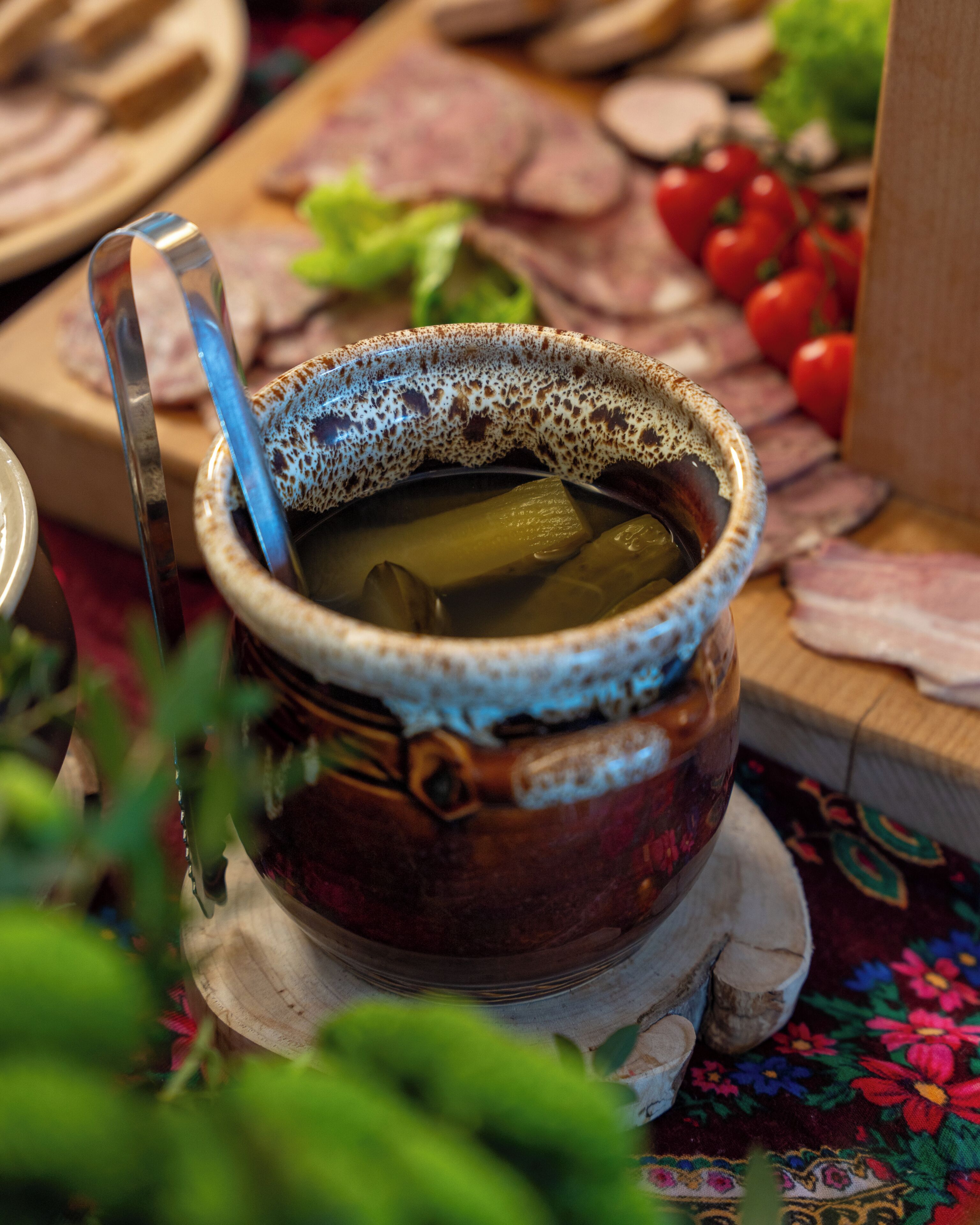 Een keramieken pot met een lepel, omringd door etenswaren op een tafel.