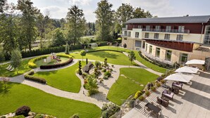 Un jardín ajardinado con área de juegos, un edificio con balcones y mobiliario exterior.
