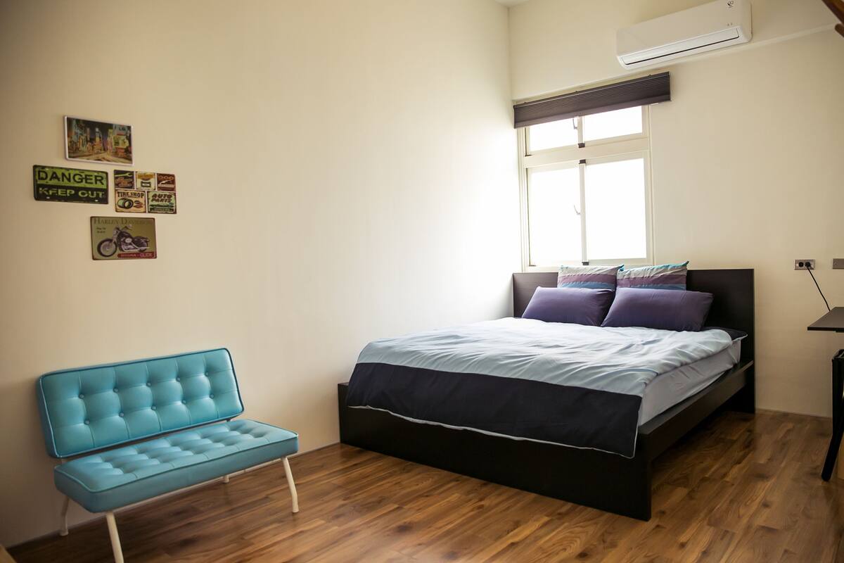 A bedroom with a bed, a blue bench, and wall decorations.