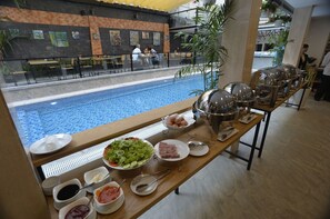 Buffet med udsigt til poolen, med forskellige retter og tilbehør.
