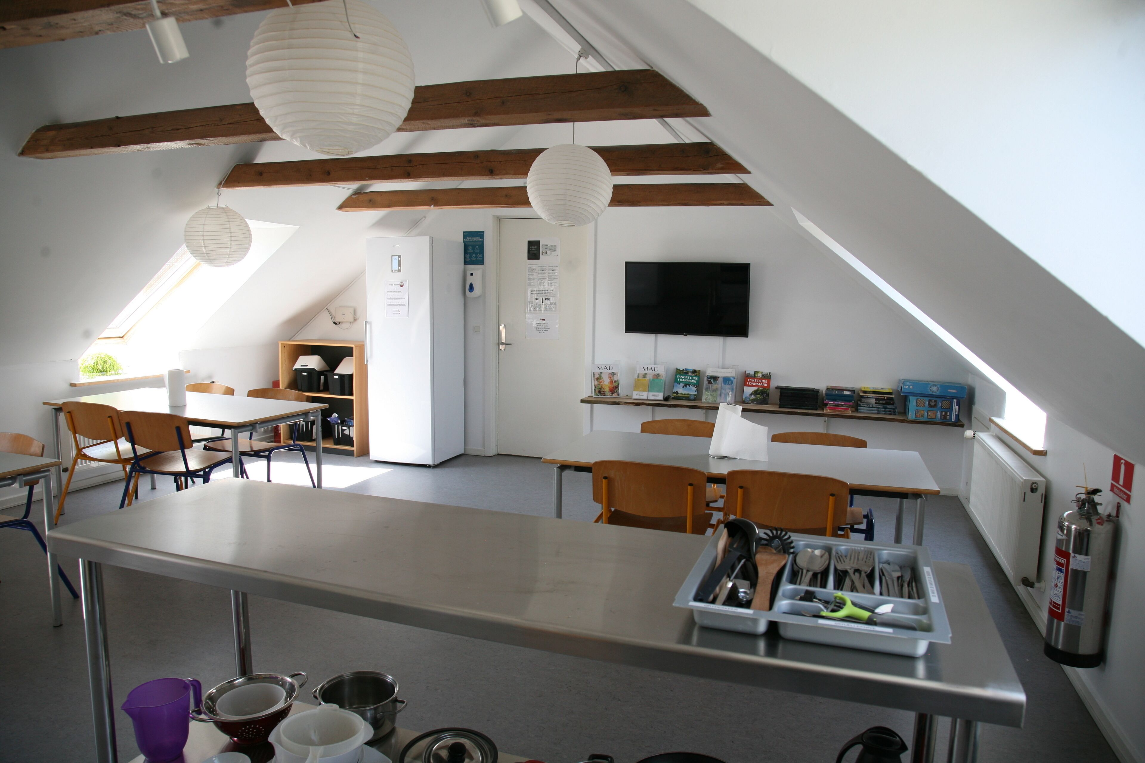 Una cocina moderna con una encimera larga, vigas de madera y un televisor montado en la pared.