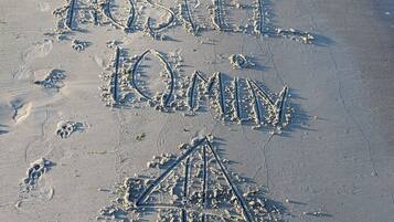 Huellas e ilustraciones hechas a mano sobre una playa arenosa.