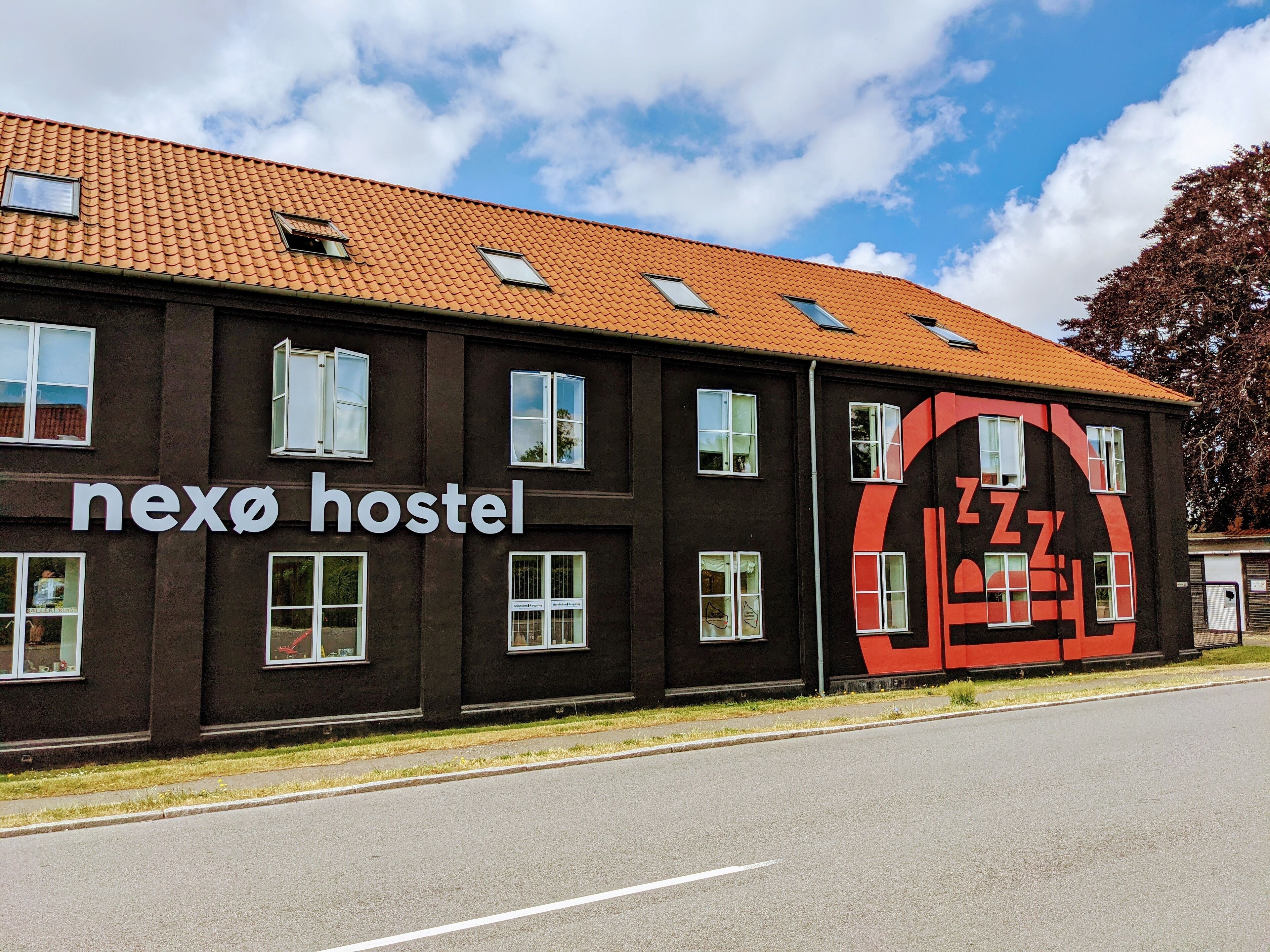 A hostel building with a dark facade and a tiled roof.