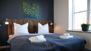 Un lit bien fait, avec une couette bleue, deux oreillers blancs et deux serviettes pliées.