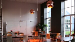 Une salle de conférence moderne dotée de planchers en bois, d’un tableau blanc et de tables avec des chaises.