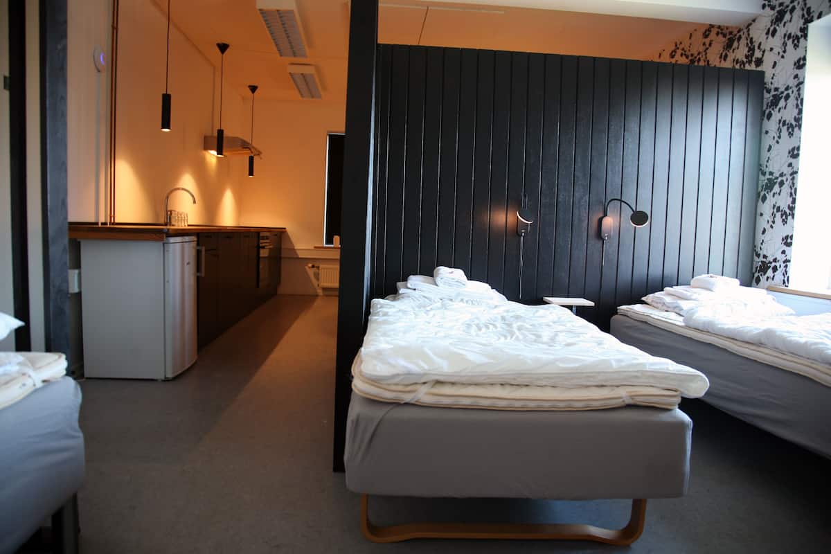 Ein modernes Hotelzimmer mit Bett, einer kleinen Küchenzeile und einer Wand in dunklem Holz.