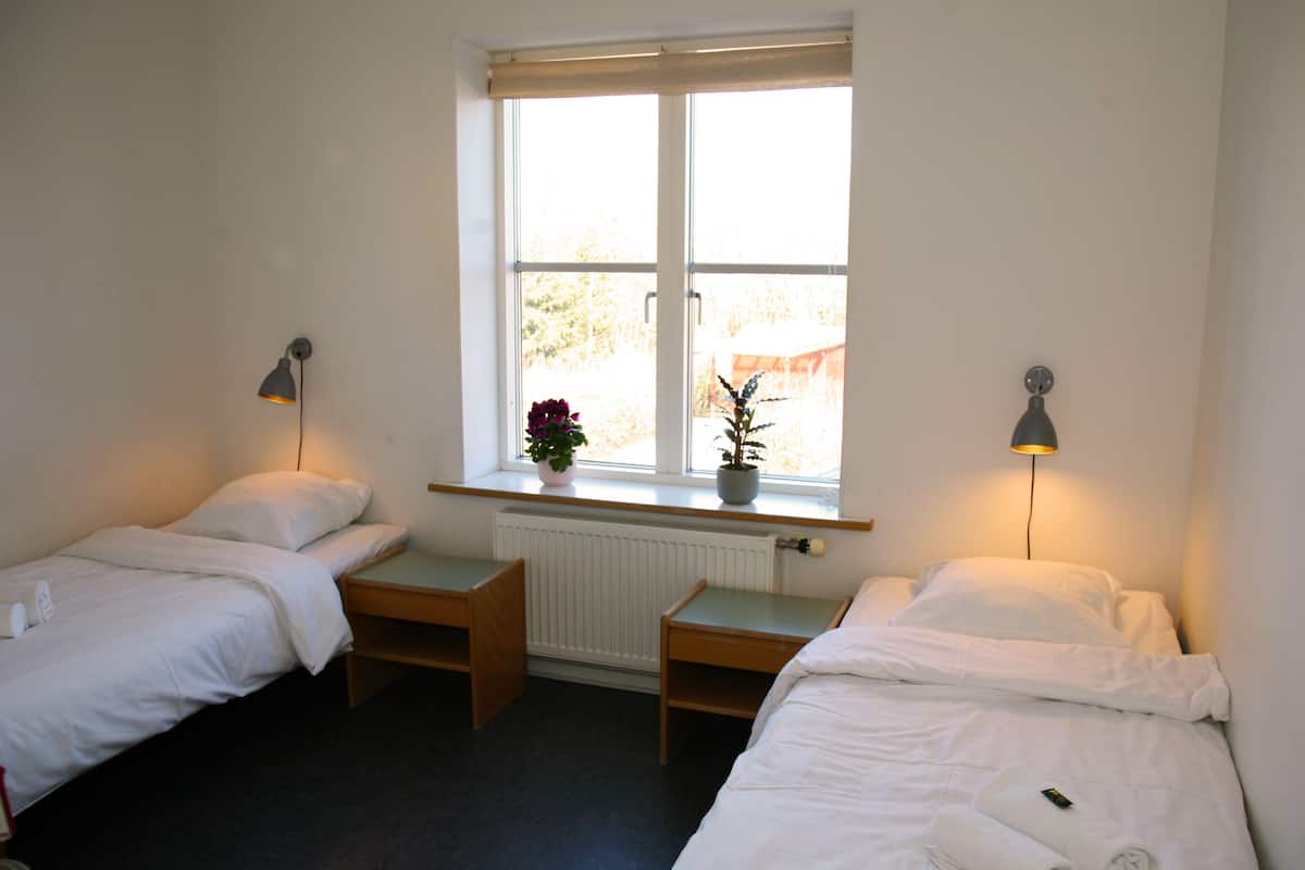 Ein Doppelzimmer mit zwei Betten, einem Fenster mit Blick und einer Heizung.