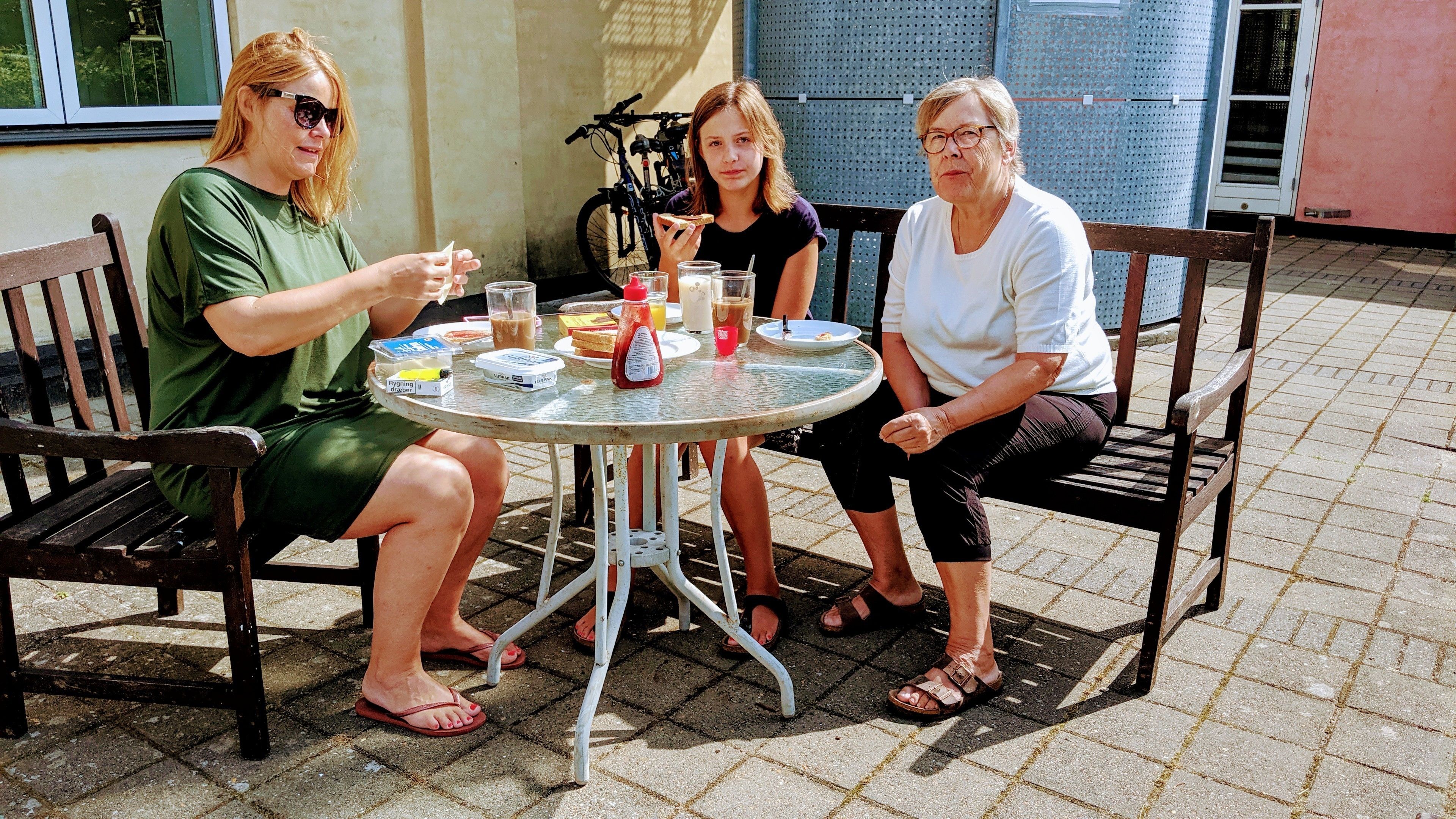 Tres personas sentadas alrededor de una mesa redonda con diversos alimentos y bebidas.