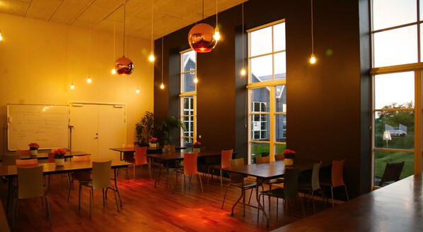 A conference room with a whiteboard, tables, chairs, and large windows. - Nexø Hostel (Nexø)