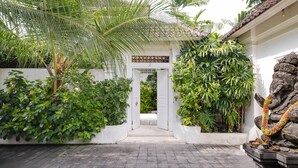 A traditional gate with a number sign, surrounded by lush greenery and a stone elephant statue.