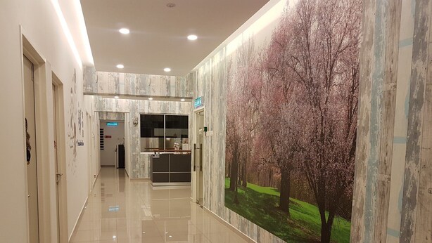 A hallway with a tiled floor, a reception desk, and a large wall mural of trees. - Dreamcatchers Home (Kuantan)