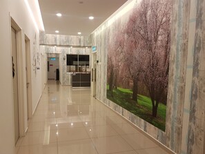 Un pasillo con suelo de baldosas, una recepción y un gran mural de árboles en la pared.