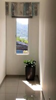 Un corridoio stretto con una finestra, una pianta in vaso e un soffitto in legno.
