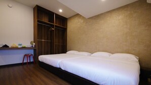 A hotel room with a large bed, a wooden wardrobe, a small stool, and a desk with toiletries. - Dreamcatchers Home (Kuantan)