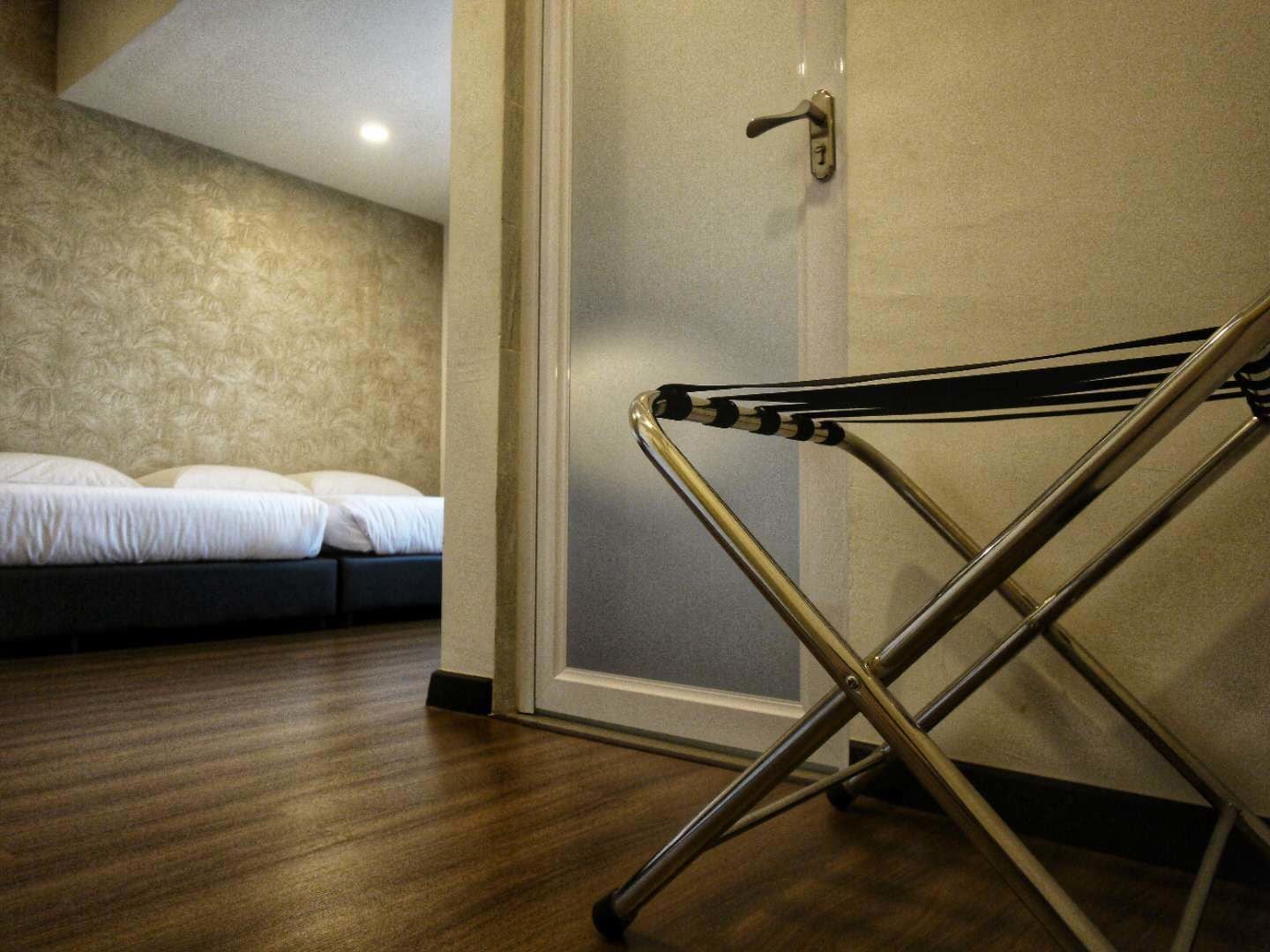 Une pièce avec un lit, une porte dotée d’une poignée et une chaise pliante en métal.
