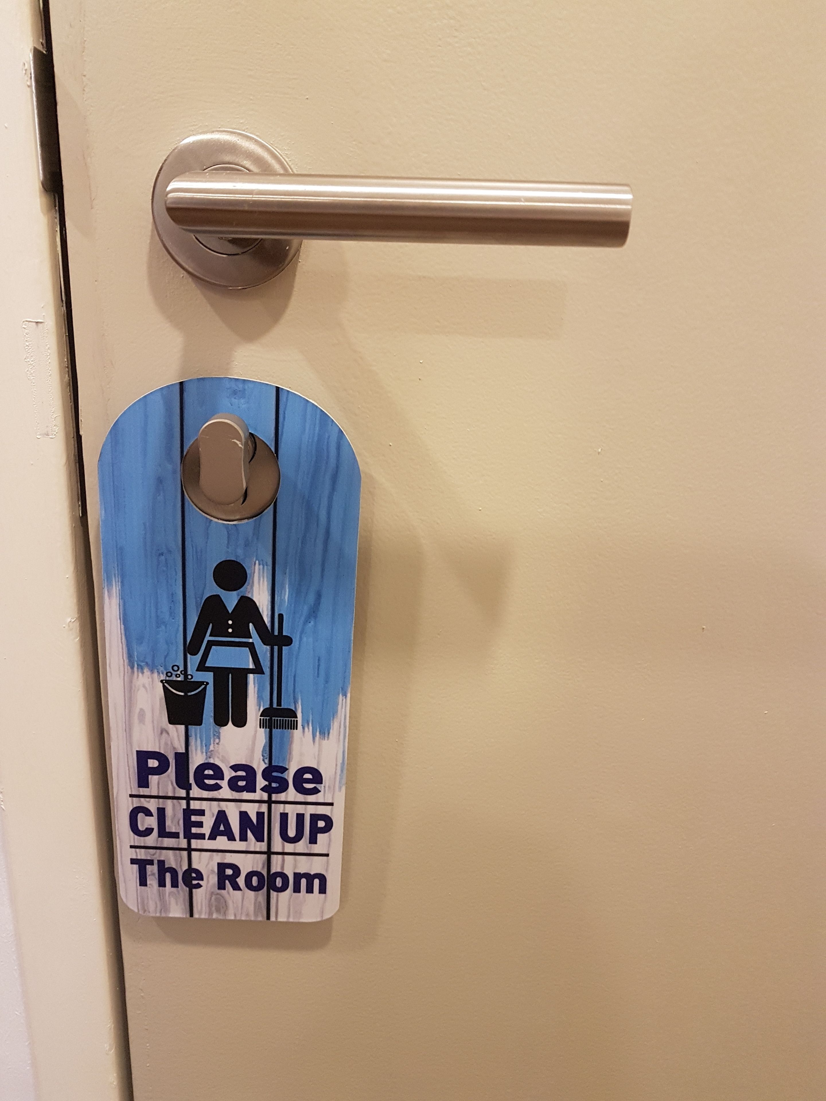 A door with a sign requesting guests to clean up the room.