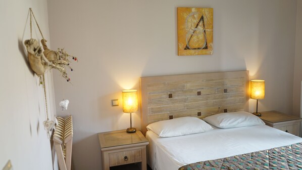 A neatly made bed with white linens, two bedside lamps, a wooden headboard, and a wall-mounted painting.