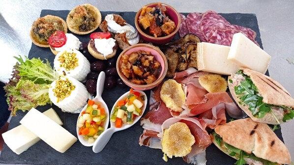 A variety of cheeses, cured meats, and vegetables on a slate board. - TerreAmare Agriturismo (Nardò)