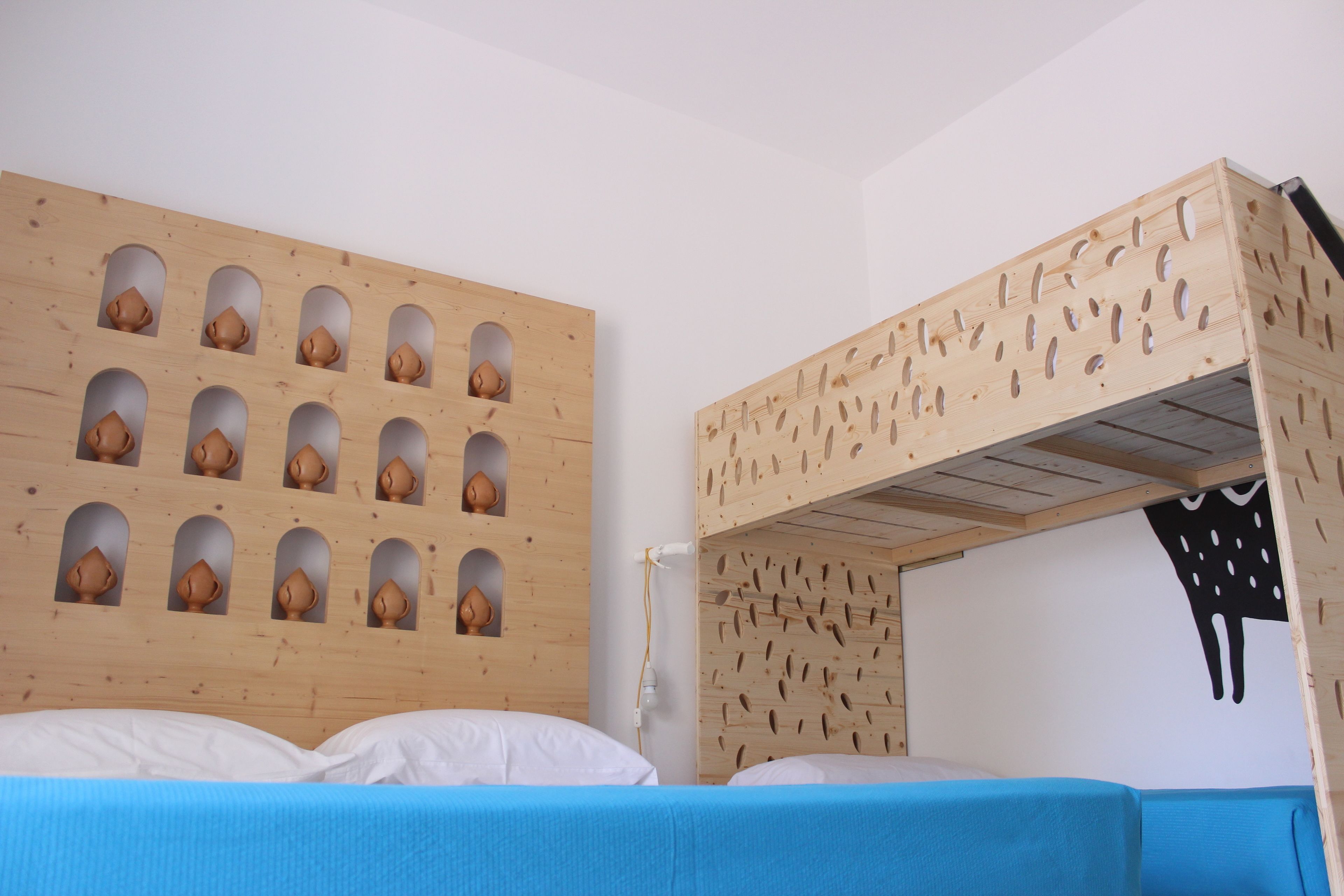 A bunk bed with a wooden headboard featuring multiple small, rounded cutouts.
