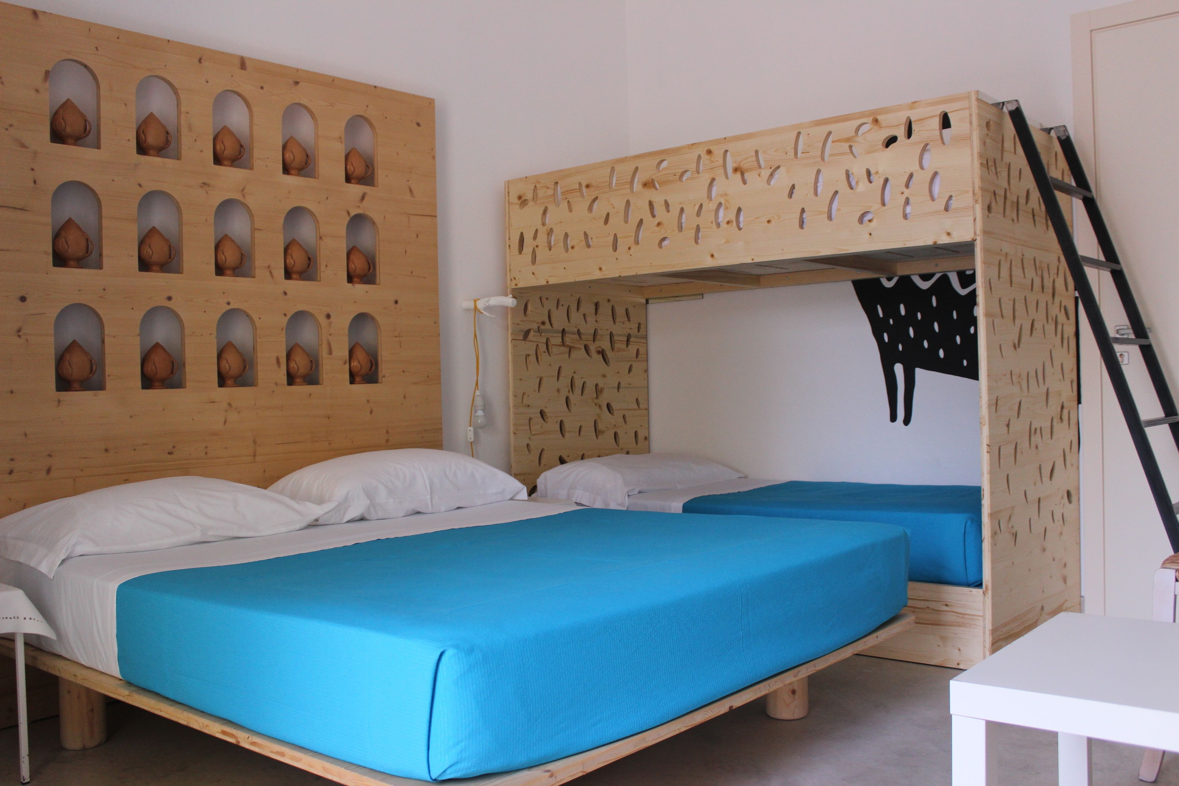 A room with two bunk beds, a wooden headboard with cut-out patterns, and a white table.