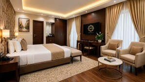 Habitación de hotel con cama, escritorio, silla, televisión y planta.