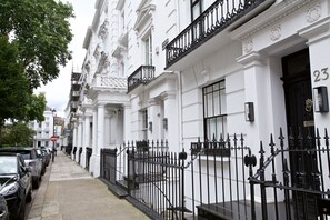 Fileira de edifícios brancos com grades de ferro preto e números nas portas.