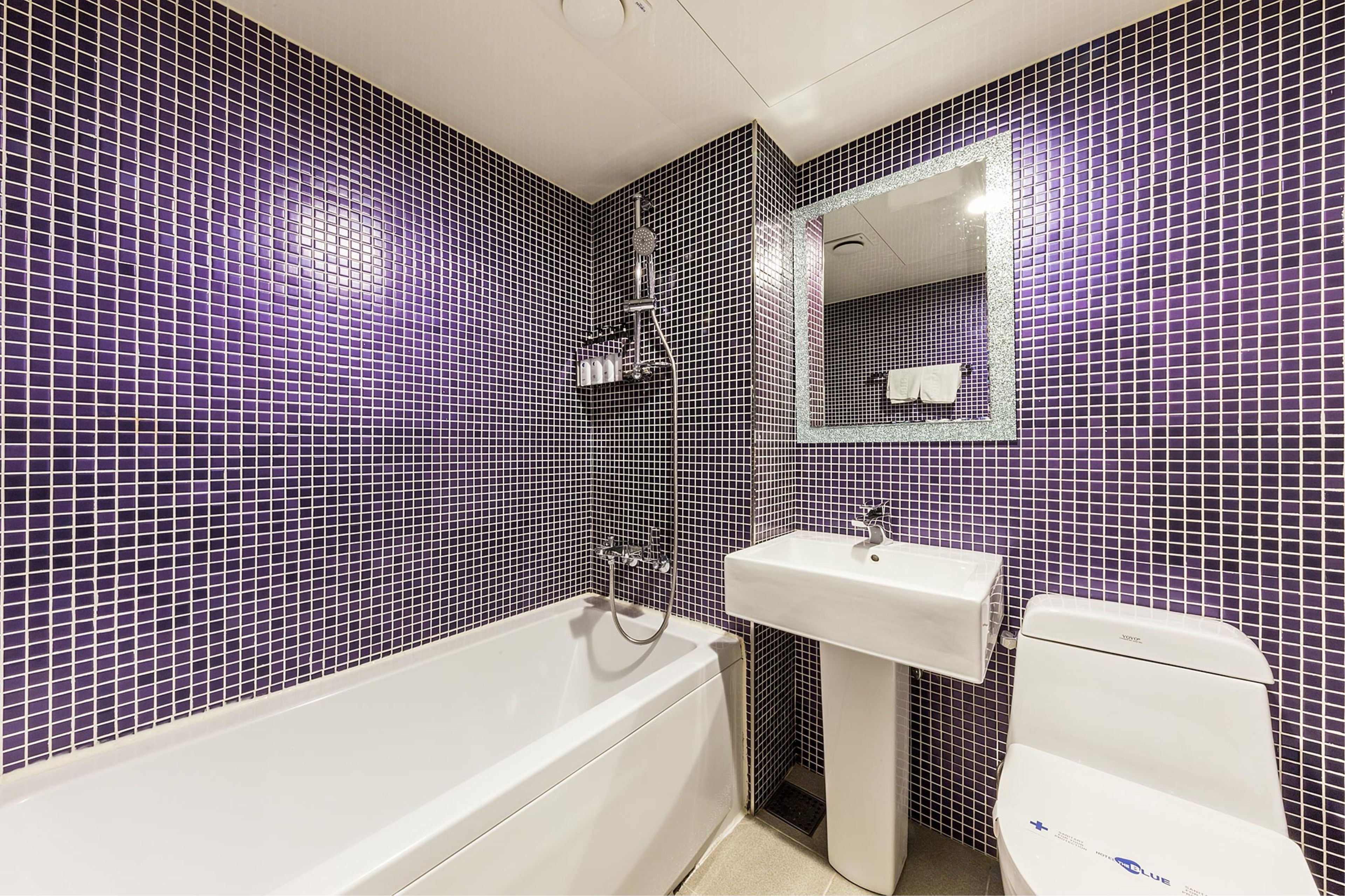 Et badeværelse med badekar, vask og toilet, alt sammen med hvide installationer.