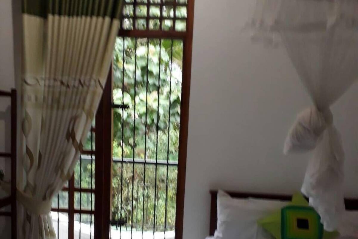Une chambre avec un lit, une fenêtre donnant sur un paysage verdoyant et un rideau.