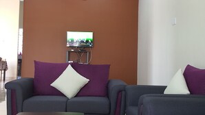 A living room with two sofas, a coffee table, a TV, and a ceiling fan. - JF Wadi Sofea Homestay (Kuala Terengganu)