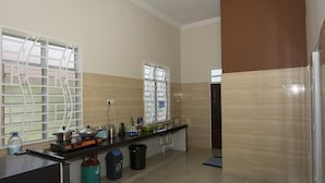 A modern kitchen with a black countertop, stainless steel appliances, and a window with a white grid. - JF Wadi Sofea Homestay (Kuala Terengganu)