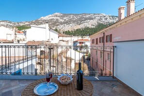 Ein Balkon mit einem Korbstuhl, einer Flasche und einem Glas Rotwein.