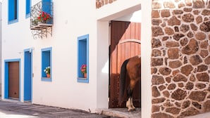 A building with blue-framed windows, a stone wall, and a wooden door. - Ghivine Albergo Diffuso (Dorgali)