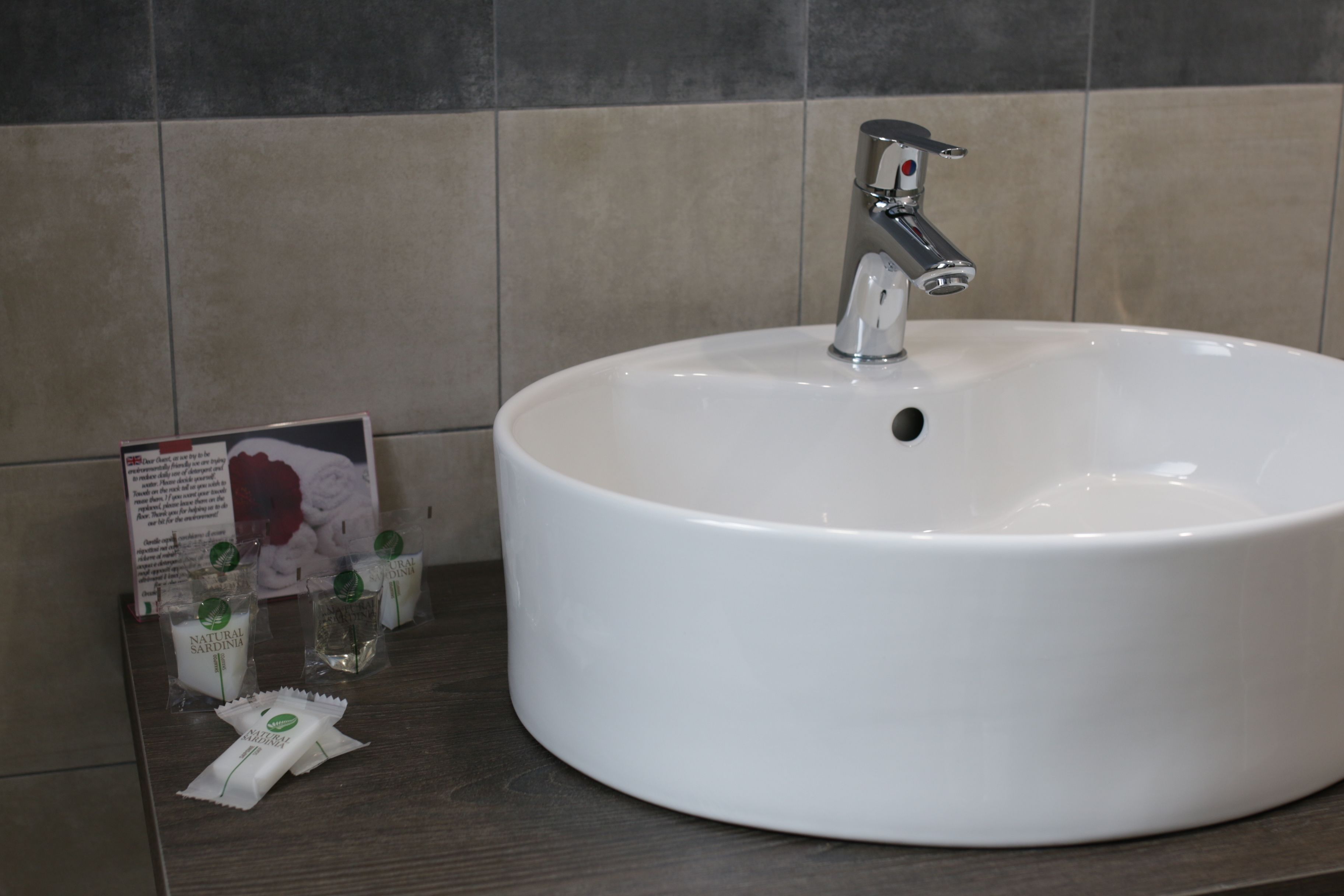 A white sink with a modern faucet, a dark wooden countertop, and a sign with product packaging.