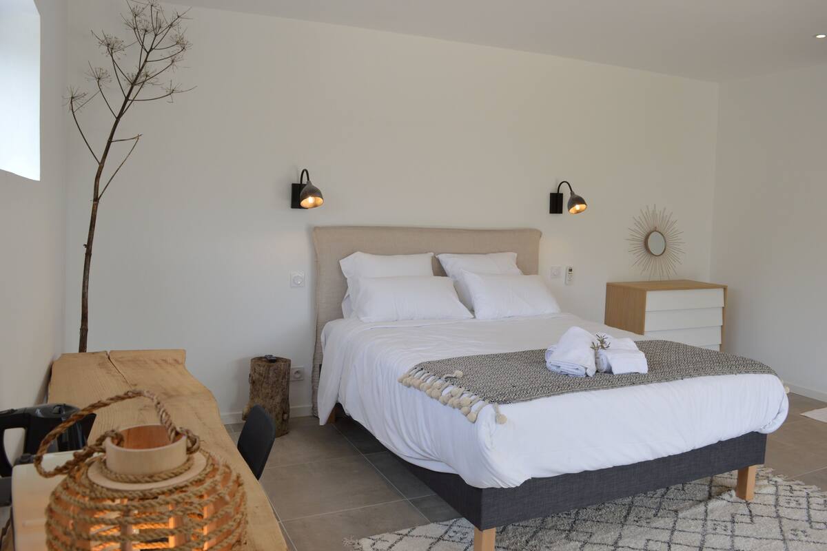 A bedroom with a bed, bedside tables, a lamp, a mirror, and a decorative branch.