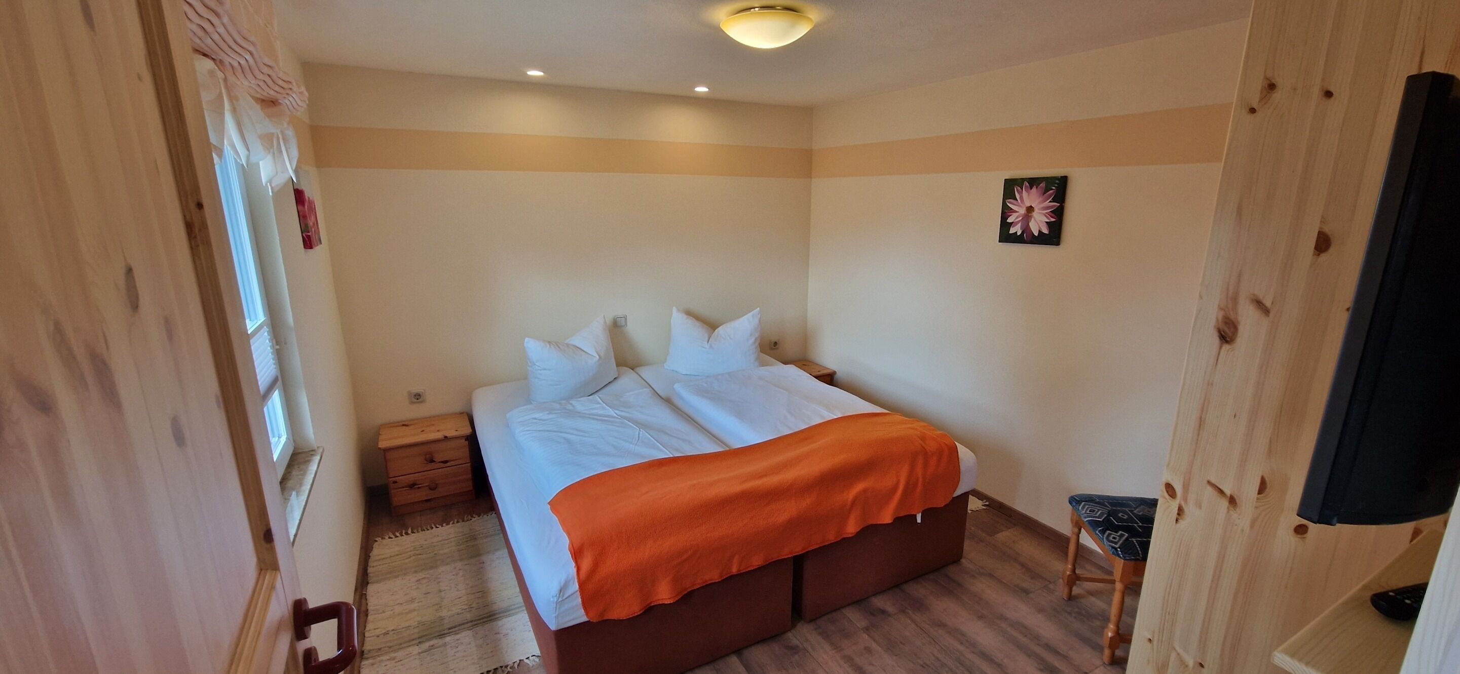 A bedroom with a bed, a nightstand, a dresser, and a small stool.