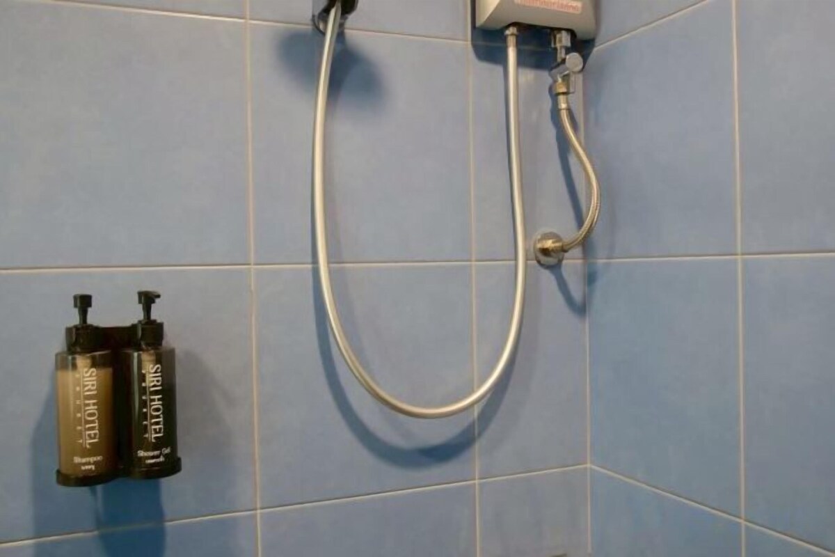 A shower with a handheld hose, a wall-mounted control panel, and two bottles of shampoo and conditioner.