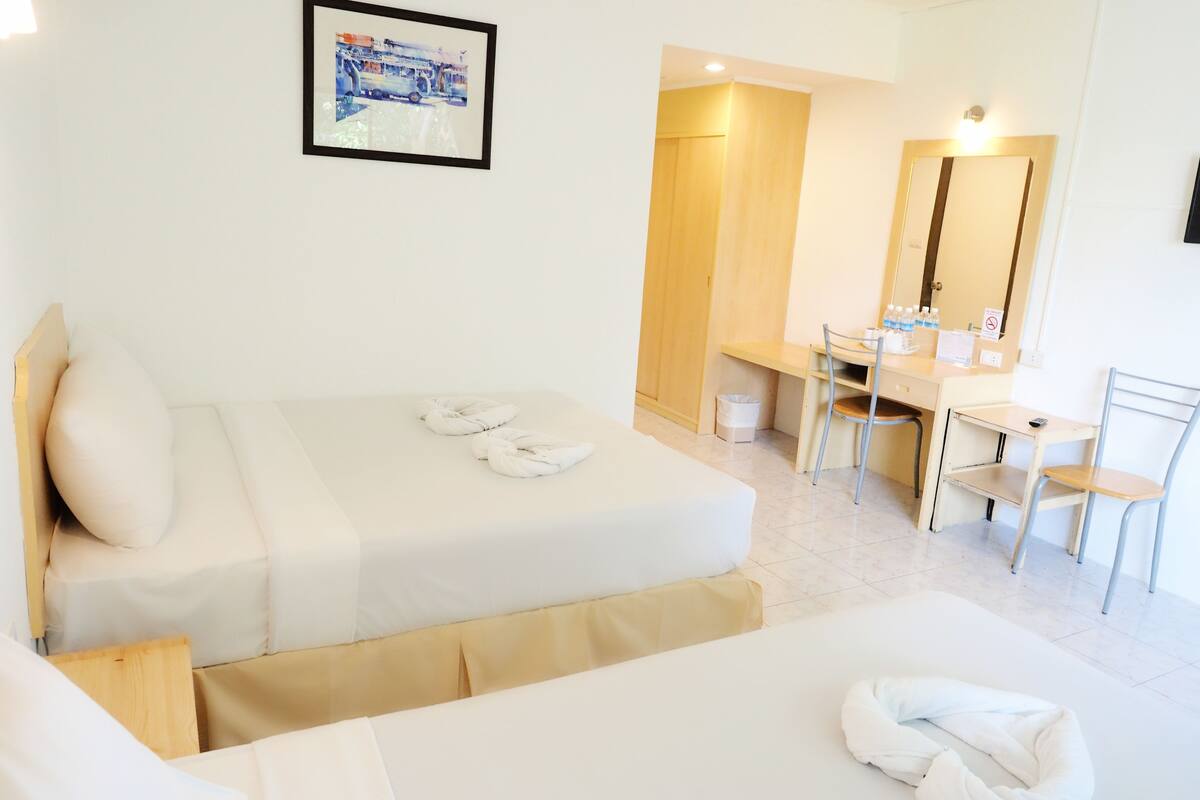 A hotel room with two beds, a desk, a chair, a mirror, and a framed picture on the wall.