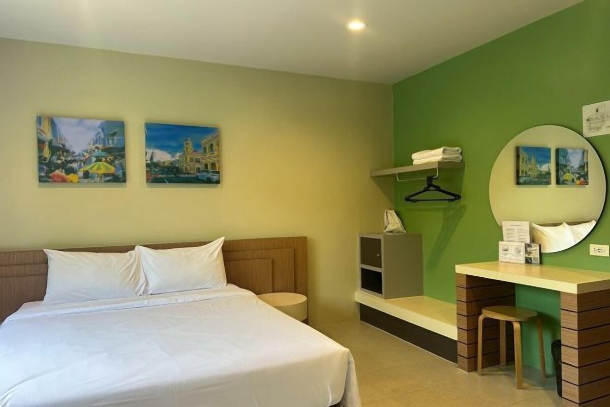 A hotel room with a bed, a desk, a chair, a mirror, and artwork on the walls.