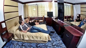 Una habitación de hotel con cama, escritorio, televisión y espejo.