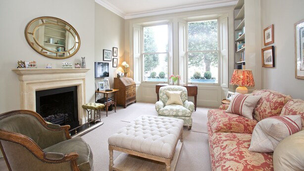 A living room with a fireplace, a large mirror, and a window with a view of trees. - A Place Like Home - Elegant flat in South Kensington (London)