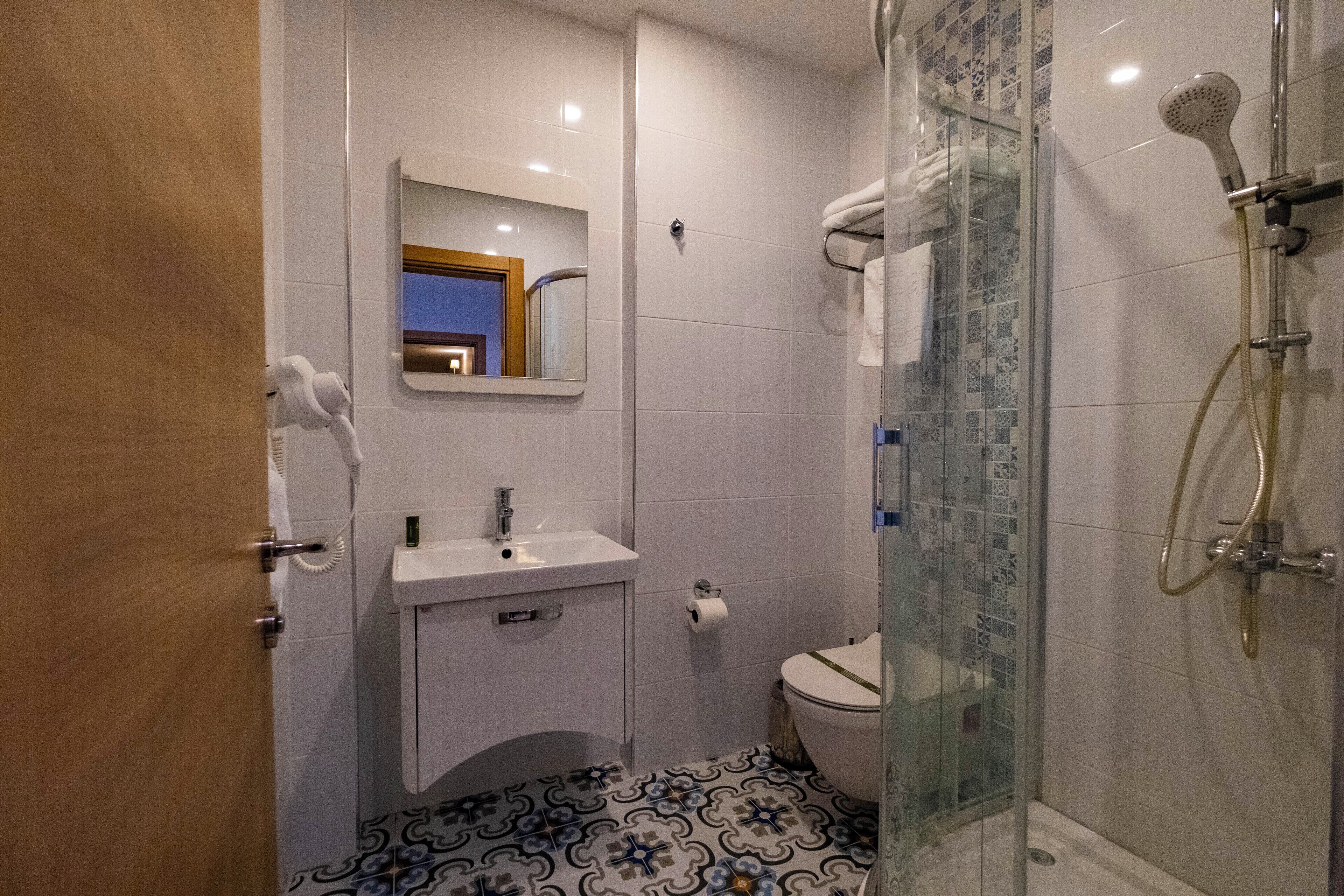 A bathroom with a shower, toilet, sink, and mirror.