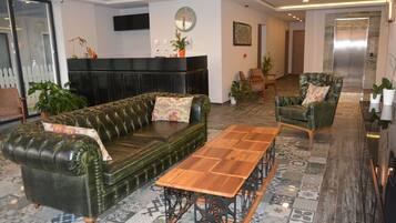 A modern lobby with a leather sofa, a wooden coffee table, and a green armchair.