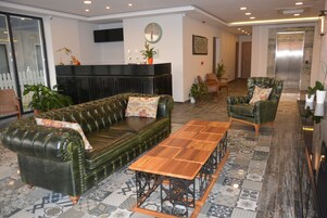 Un vestíbulo moderno con un sofá de cuero, una mesa de centro de madera y un sillón verde.