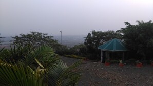 A gazebo with a green roof surrounded by potted plants and trees. - Lago Resort (Kisumu)